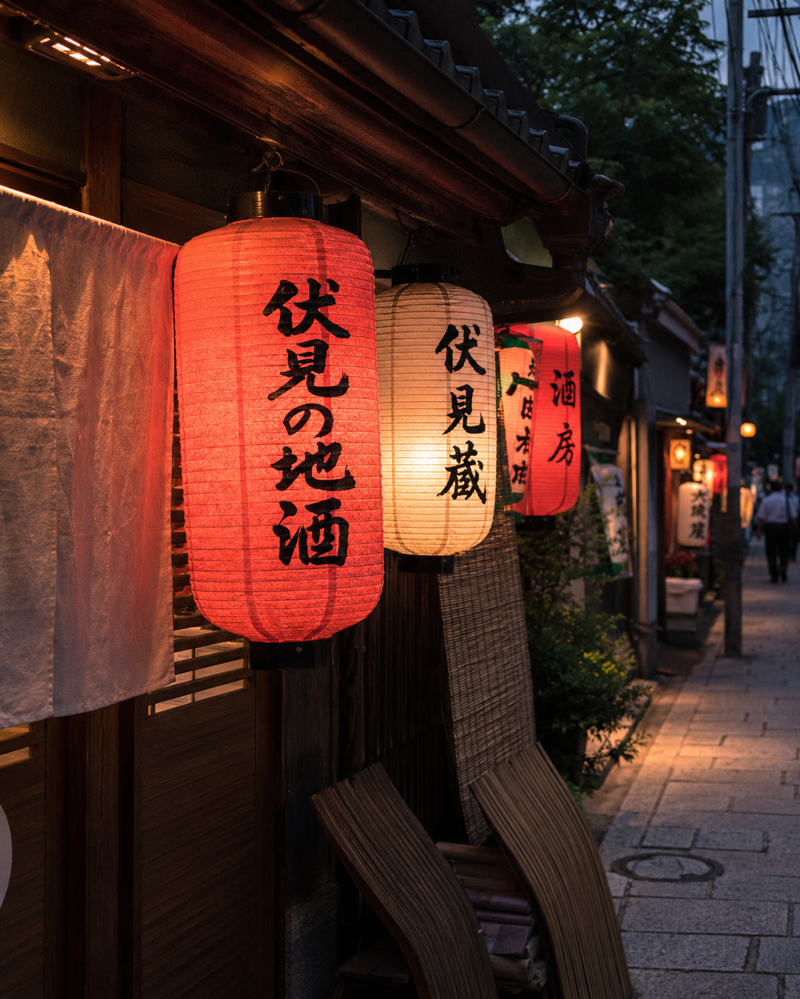 Traditional red and white Japanese paper lanterns with calligraphy glowing outside a restaurant in Kyoto at night.
